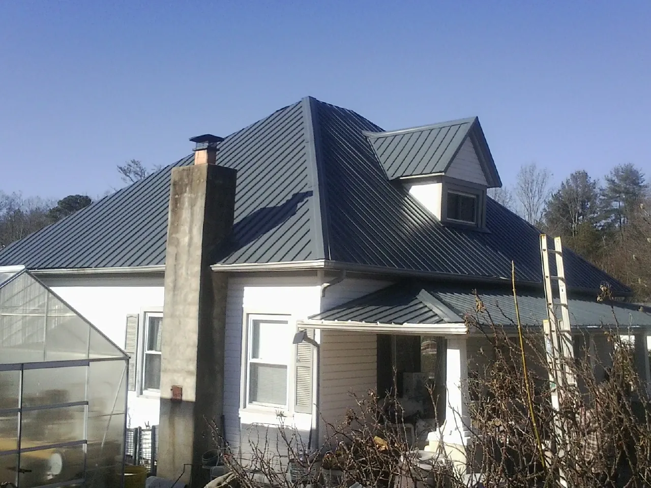 Dark blue standing seam metal roof on a white farmhouse with dormer — Slate & Tile Roof Repair by Roofing Brothers in Hickory Valley