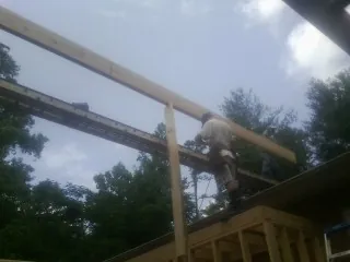 Carpenter setting a ridge beam over a new addition frame — Ice Dam Removal by Roofing Brothers in Hickory Valley