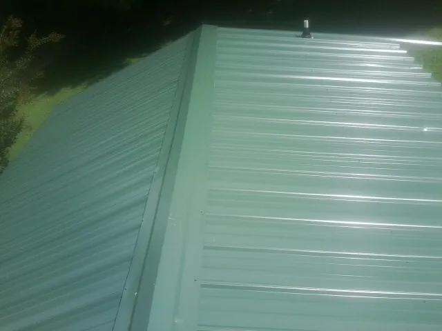 New green metal panels meeting at the ridge of a roof — Flat Roof Repair work by our crew in Hickory Valley