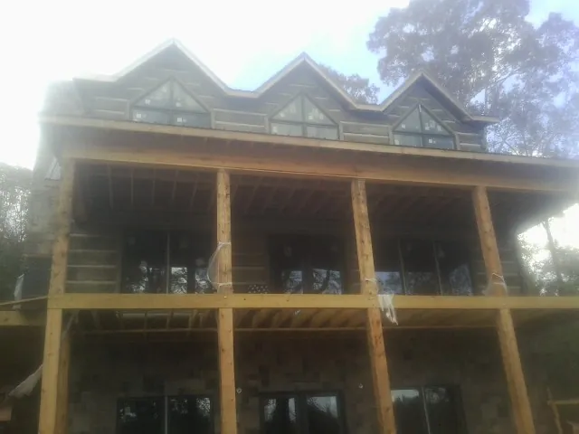 Dormers and porch framing on a large log home under construction — Roof Coating work by our crew in Hickory Valley