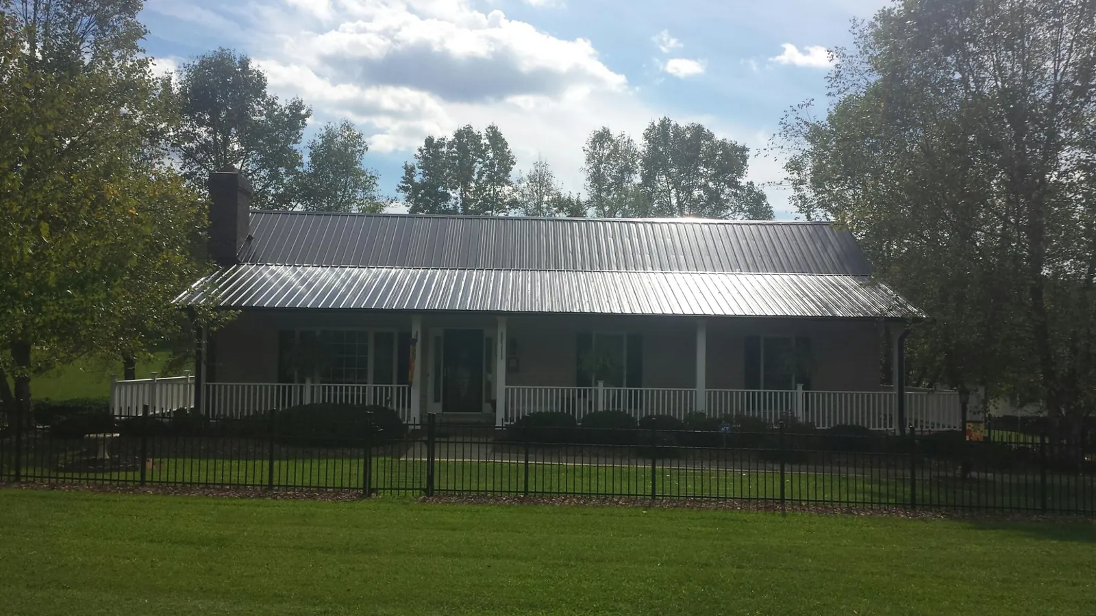 Gray metal roof on a brick ranch with a full width front porch — Gutter Guard Installation work by our crew in Hickory Valley