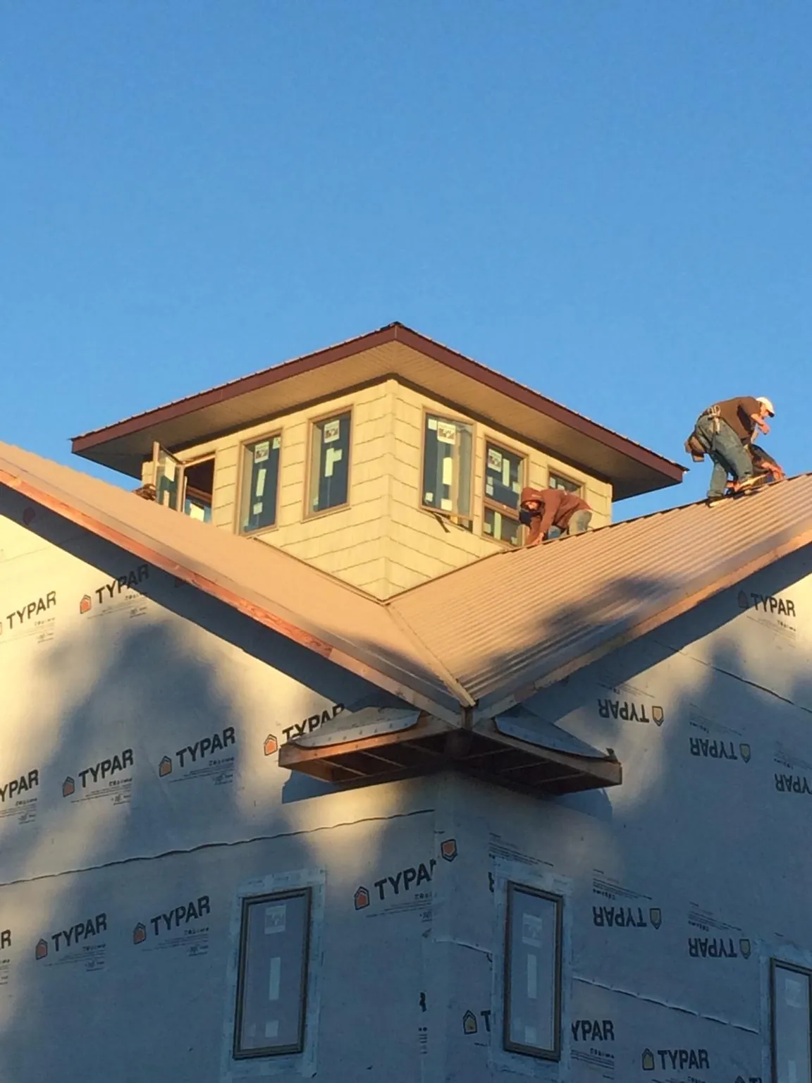 Roofers working around a rooftop cupola on a new metal roof at sunset — Roof Waterproofing in Hickory Valley by Roofing Brothers